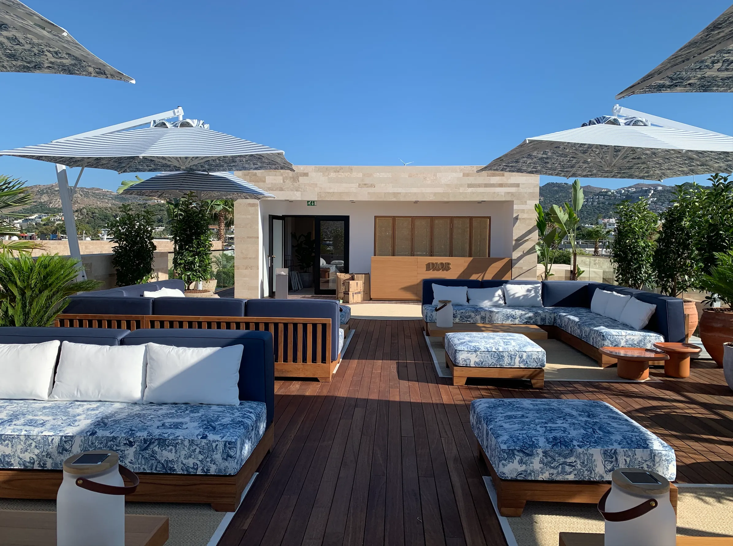 Grand airport retail hall with sculptural spiral staircase, patterned terrazzo floor, and orchid-topped display tables
